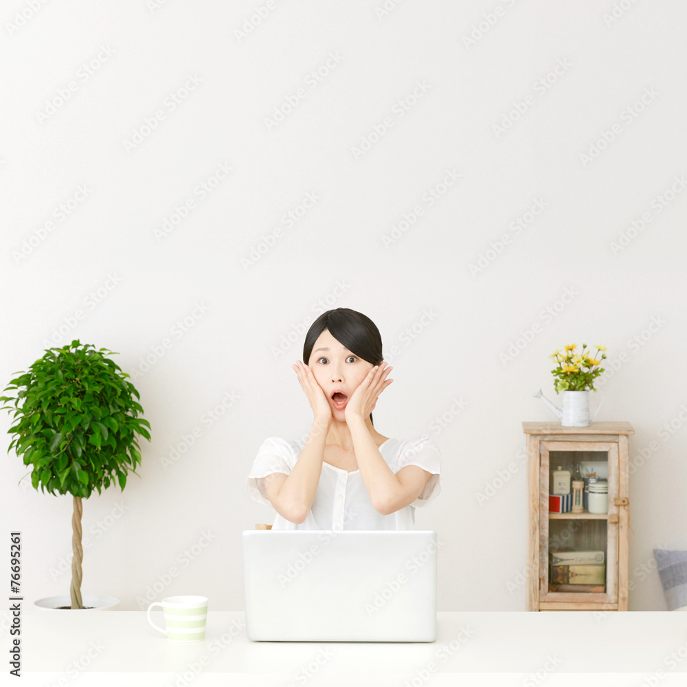 パソコンの前に座って驚く女性