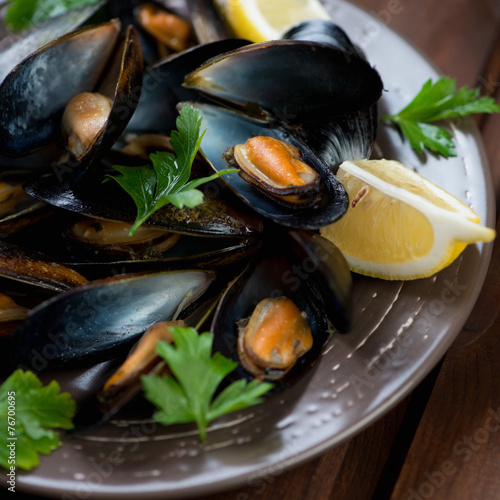 Close-up of steamed mussels served with fresh parsley and lemon