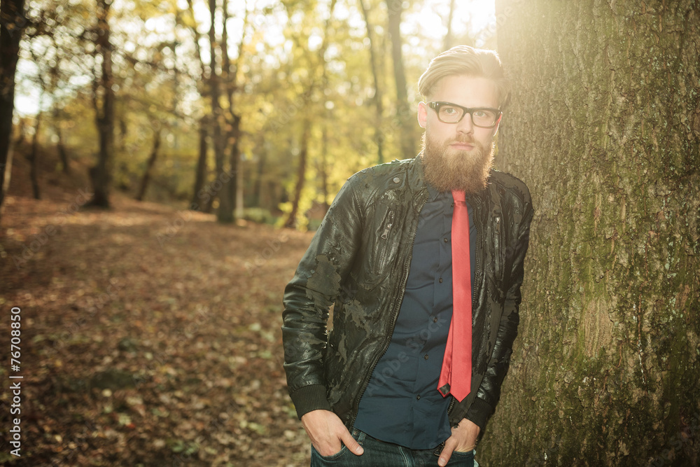 man leaning on a tree with his hands in pockets. man leaning on a tree with his hands in pockets.
