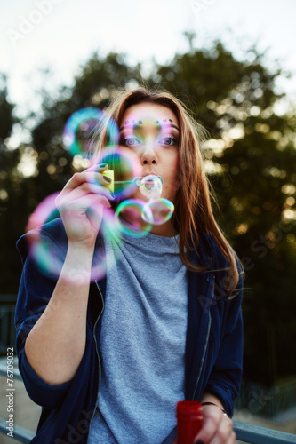 Young woman portrait blowing soap bubbles
