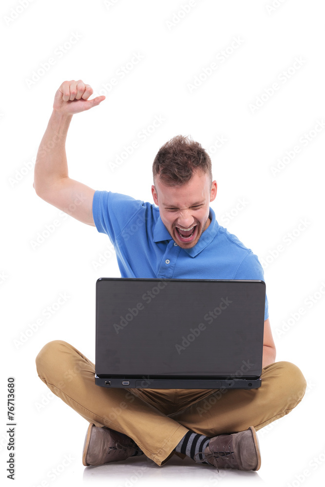 seated young casual man cheers with laptop seated young casual man cheers with laptop