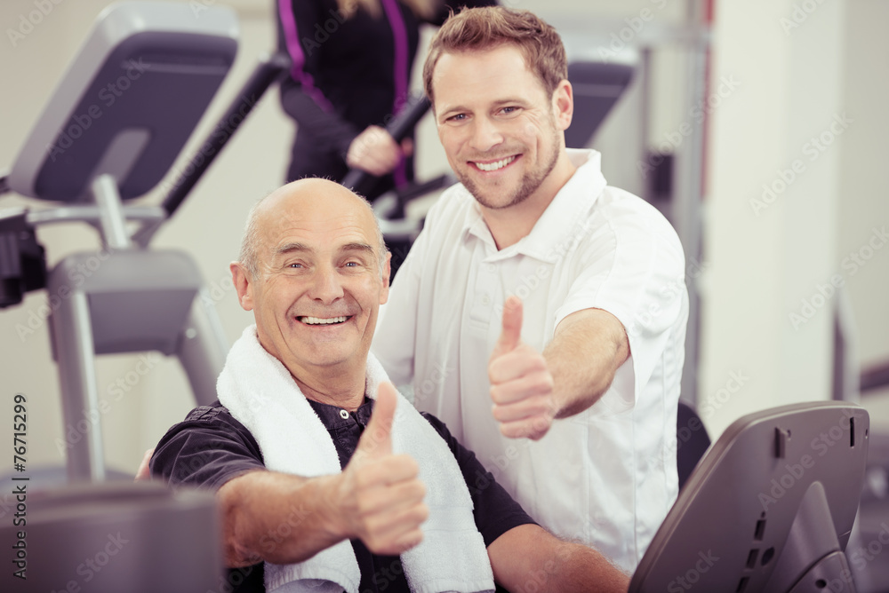 trainer und älterer kunde zeigen daumen hoch im sportstudio trainer und älterer kunde zeigen daumen hoch im sportstudio