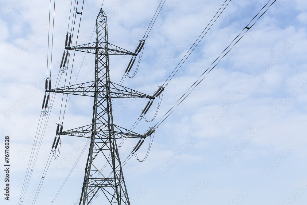 Lone power pylon against a light blue sky with clouds Lone power pylon against a light blue sky with clouds
