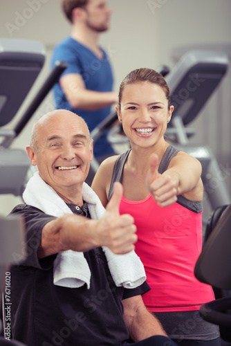 senior und junge frau zeigen daumen hoch im fitness-studio © contrastwerkstatt