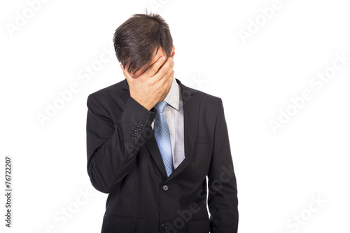 Portrait of exhausted young businessman covering his face with h