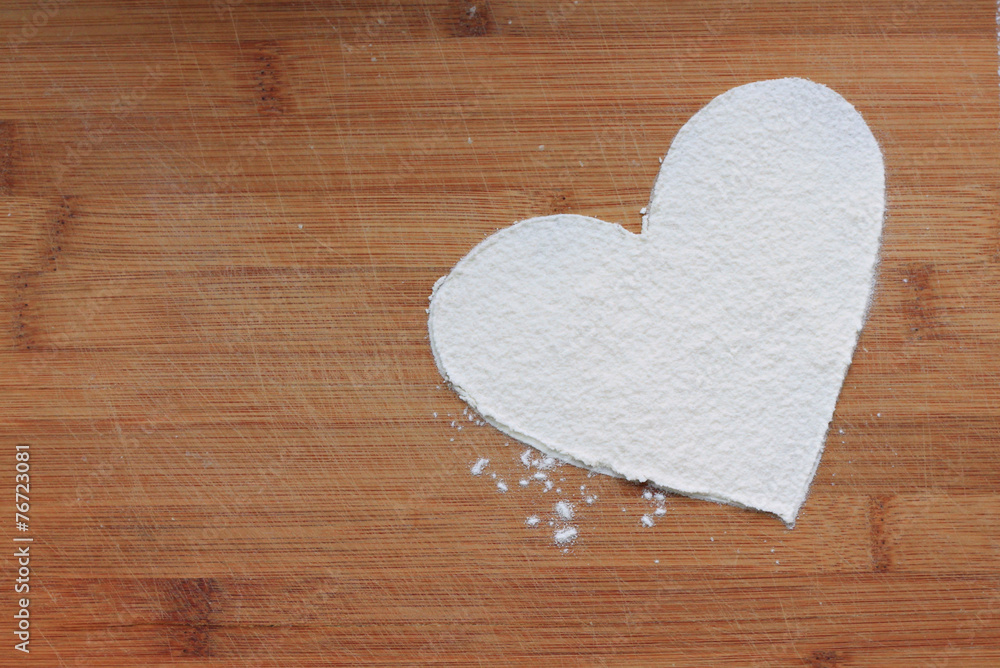 heart from white wheat flour on wooden background heart from white wheat flour on wooden background