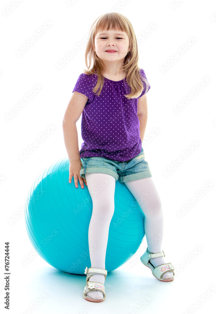 Little girl in short sports shorts sitting on the big blue. Little girl in short sports shorts sitting on the big blue.