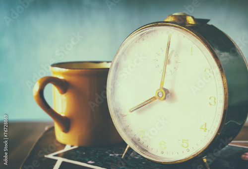 close up image of old clock and cofee cup over wooden table. ima