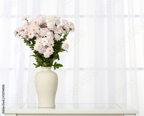 Beautiful bouquet of flowers in vase on window background