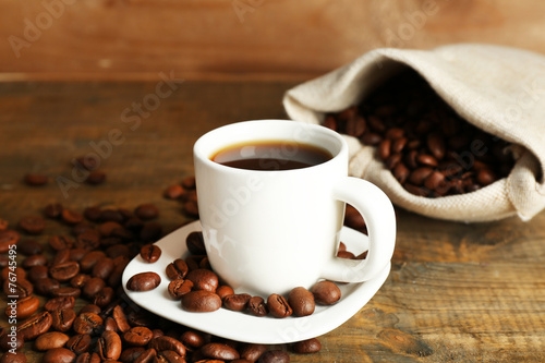 Cup of coffee with beans on rustic wooden background