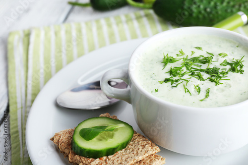 Cucumber soup in bowl on color wooden table background