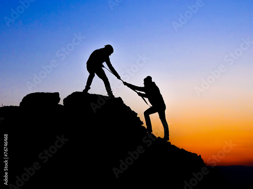 Silhouette of helping hand between two climber