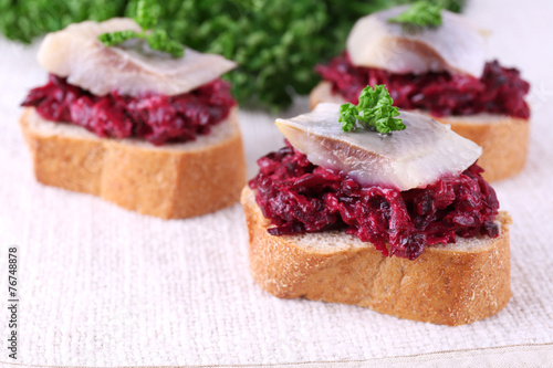 Rye toasts with herring and beets on tablecloth background