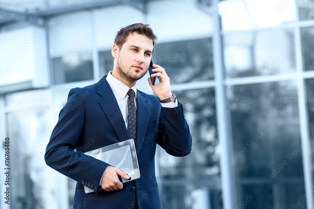Attractive young businessman using a cell phone, smiling. Taken Attractive young businessman using a cell phone, smiling. Taken