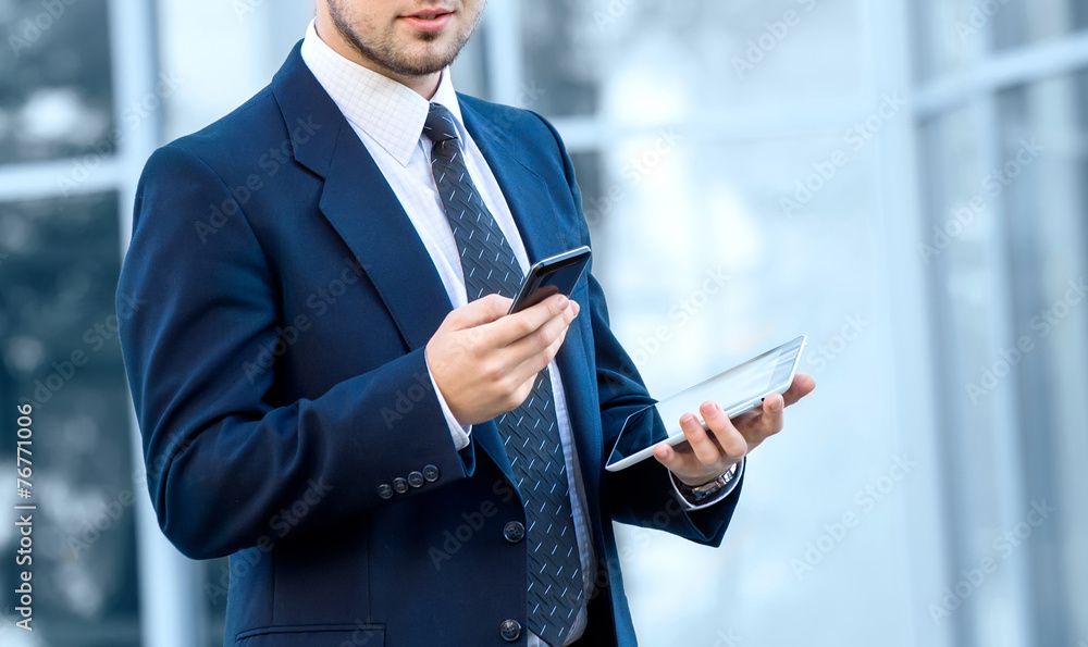 Fototapeta premium Attractive young businessman using a cell phone, smiling. Taken