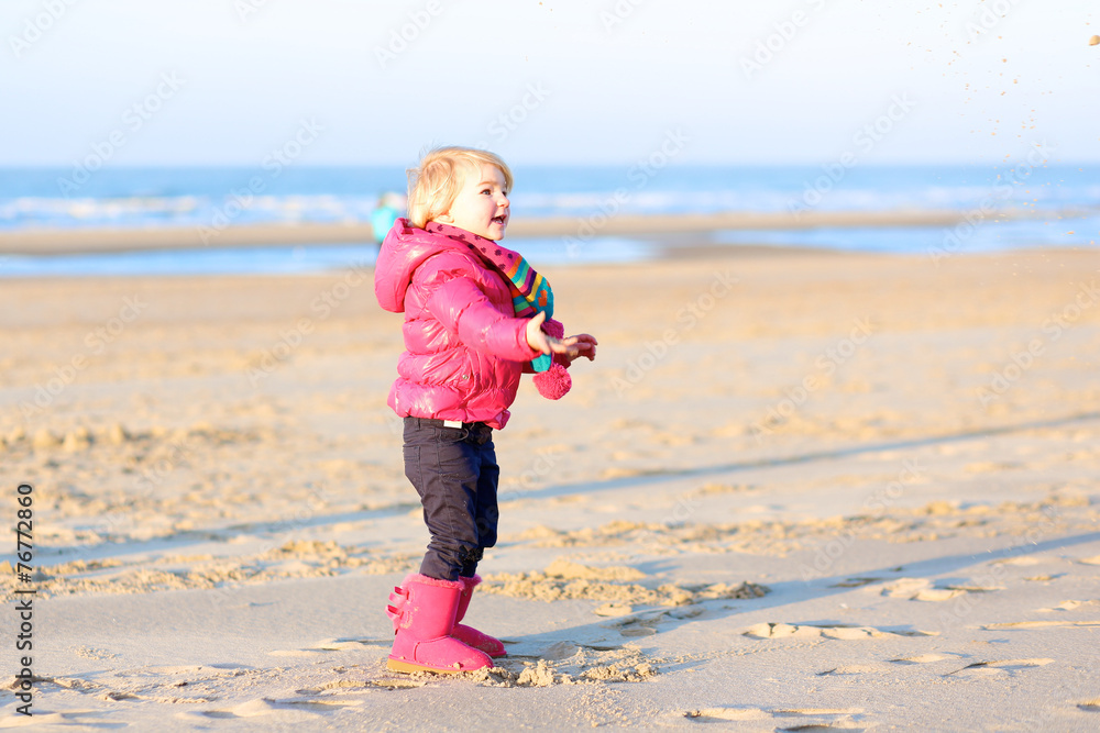 Little girl playing on the beach at winter or spring Little girl playing on the beach at winter or spring