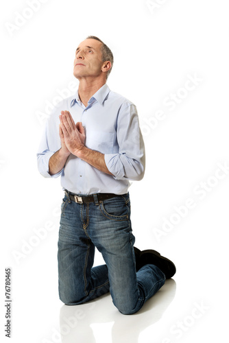 Fototapeta Man kneeling and praying to God