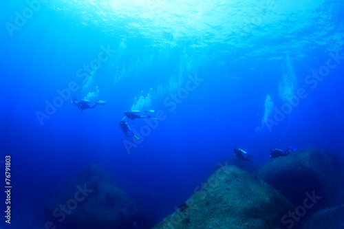 Scuba divers swim over coral reef in ocean