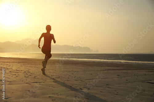 young woman running on sunrise beach