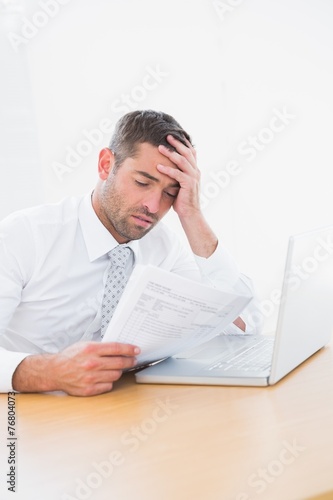 Confused businessman looking at his paper