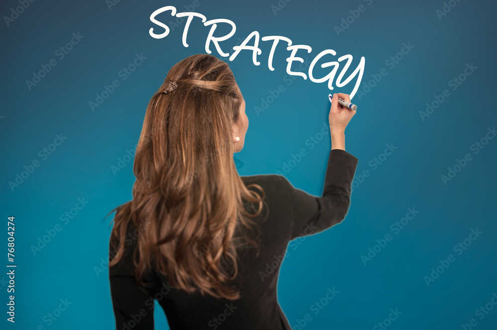 Businesswoman writing a Strategy on a wall - Stock Image Businesswoman writing a Strategy on a wall - Stock Image