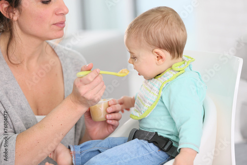 Mother giving fruit sauce to baby boy photo