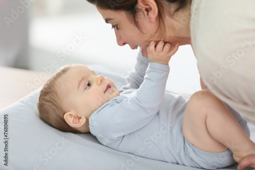 Mommy cuddling baby boy on changing table