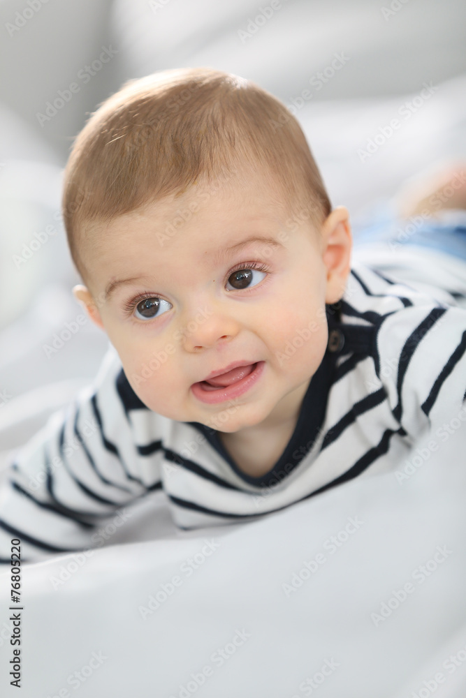 Cheerful baby boy laying over bed