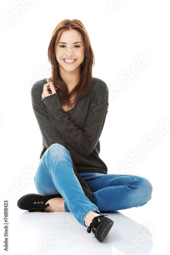 Casual young woman sitting on white floor