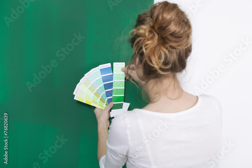 Frau mit Farbtafeln vor gruener Wand photo