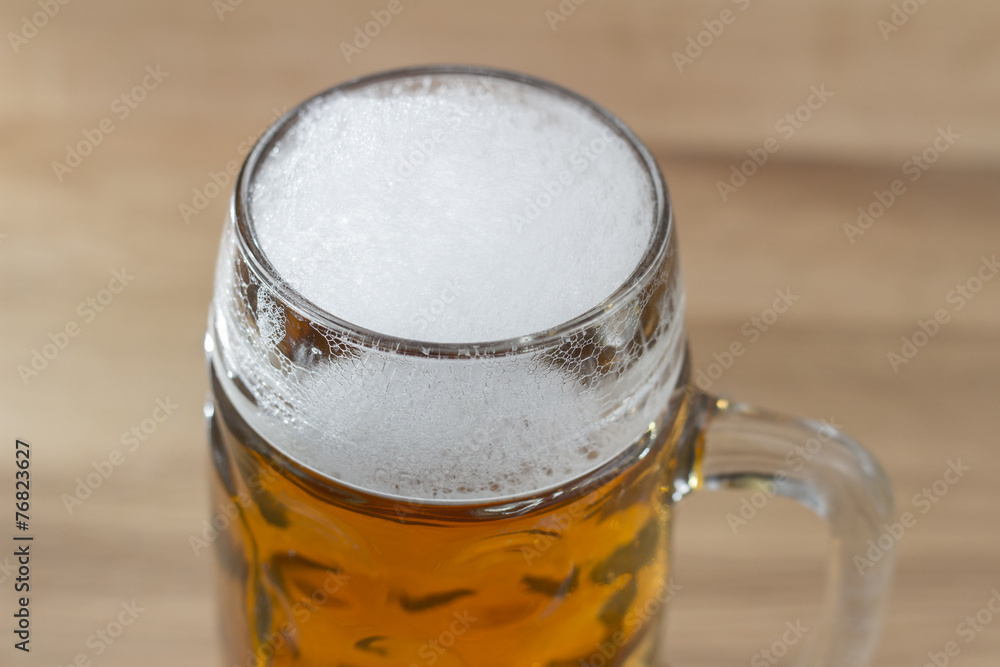 Beer with a frothy head in a glass beer mug Beer with a frothy head in a glass beer mug