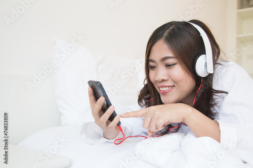 Young happy asian woman using smartphone and listen music