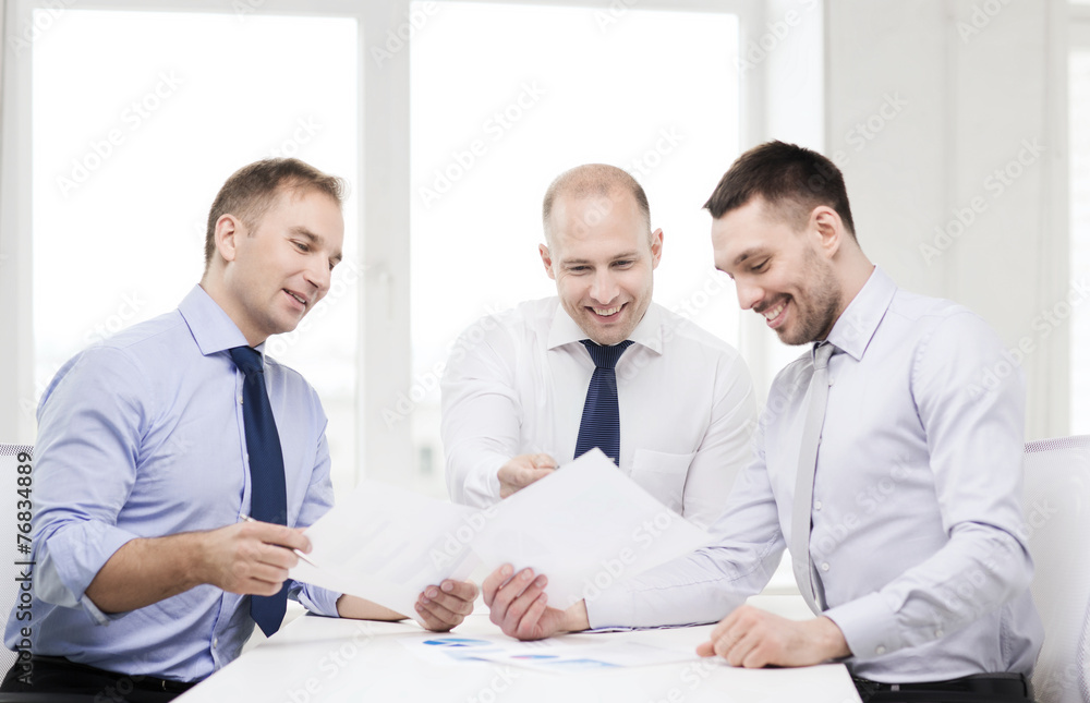 smiling businessmen with papers in office smiling businessmen with papers in office