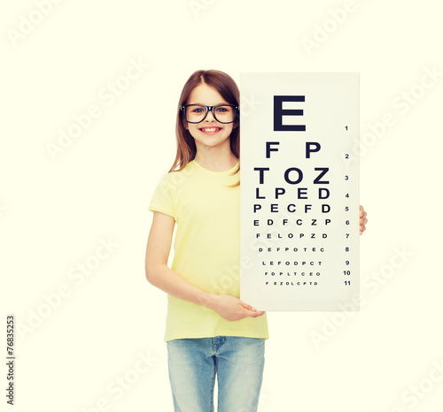 little girl in eyeglasses with eye checking chart