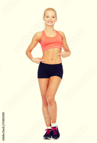 smiling sporty woman pointing at her six pack