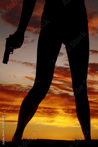 silhouette of woman legs with gun hold down