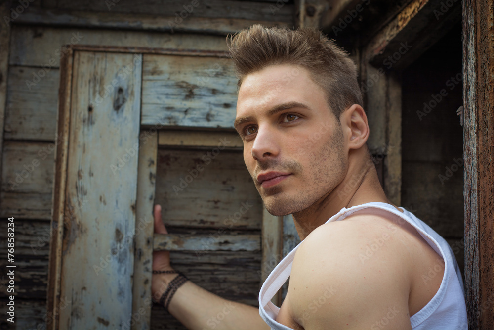 Young man against old rusty metal door and wood Young man against old rusty metal door and wood