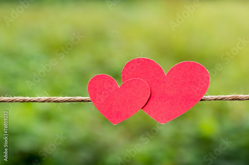 two red paper hearts hanging on the Natural background.