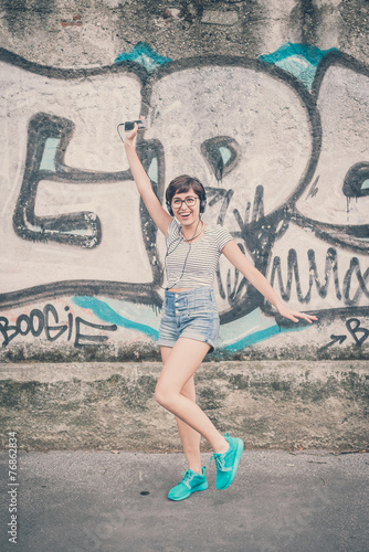 young hipster woman listening to music jumping