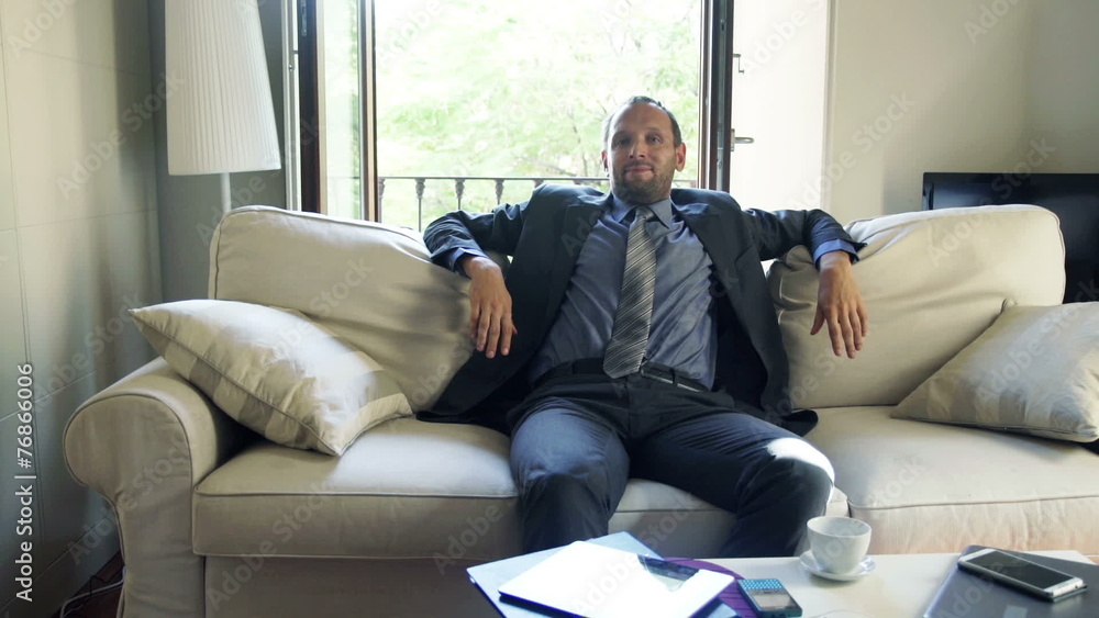 Young businessman relaxing and stretching on sofa at home Young businessman relaxing and stretching on sofa at home
