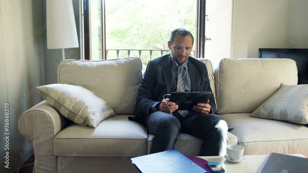 businessman watching movie on tablet computer sitting on sofa businessman watching movie on tablet computer sitting on sofa