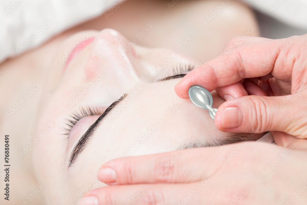 Serum capsule in front of young woman face in spa salon