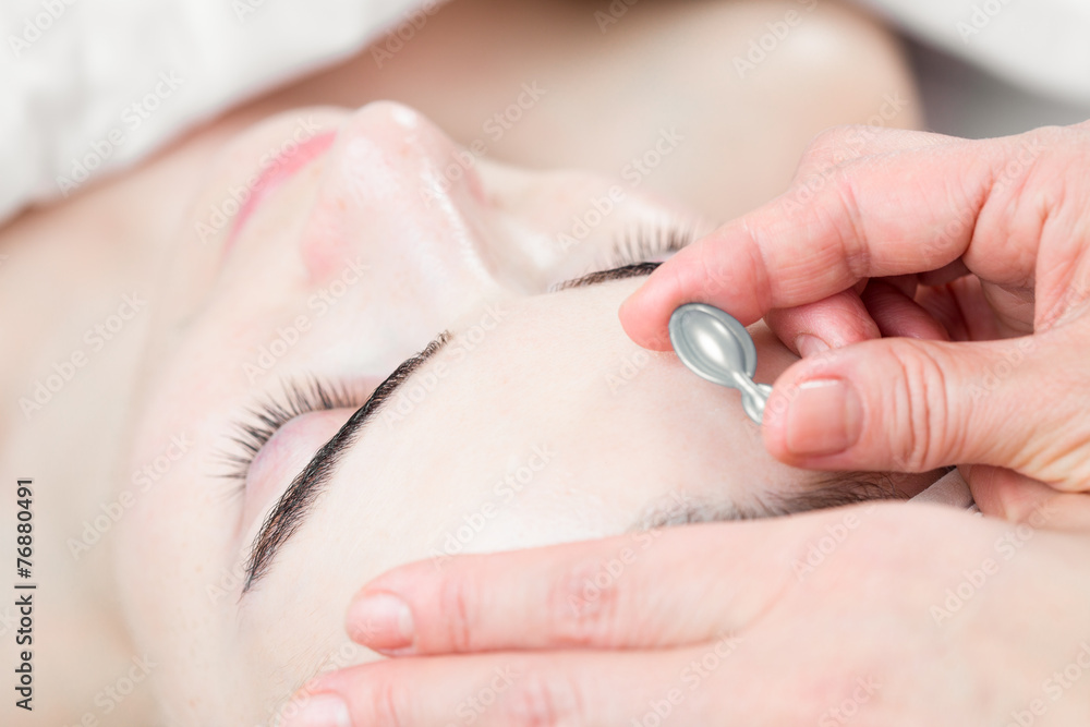 Serum capsule in front of young woman face in spa salon Serum capsule in front of young woman face in spa salon