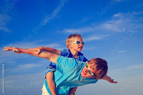 Father and son playing on blue summer sky