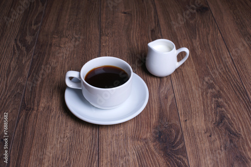 Кружка  с чёрным кофе и молочник на деревянном столе