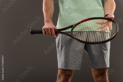 Handsome young man in polo shirt holding tennis racket © zinkevych