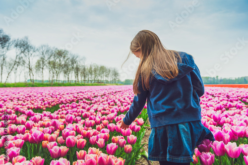 Adorable little girl playing with flowers on a tulip farm