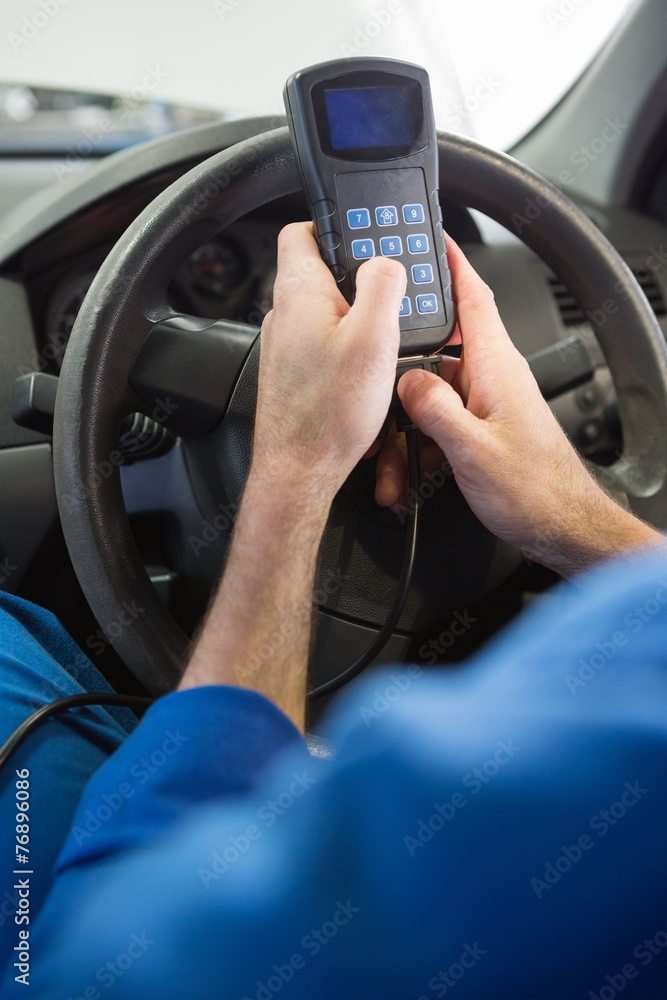 Naklejka premium Mechanik za pomocą narzędzia diagnostycznego w samochodzie