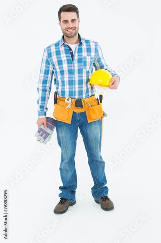 Confident handyman holding hard hat and gloves © WavebreakmediaMicro