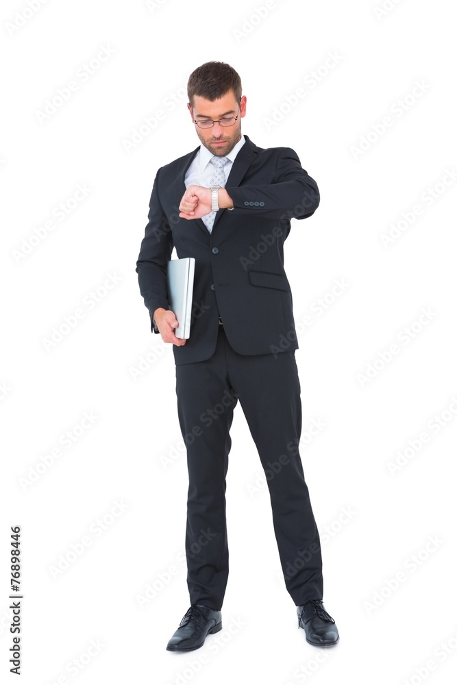 Serious businessman holding laptop checking time Serious businessman holding laptop checking time